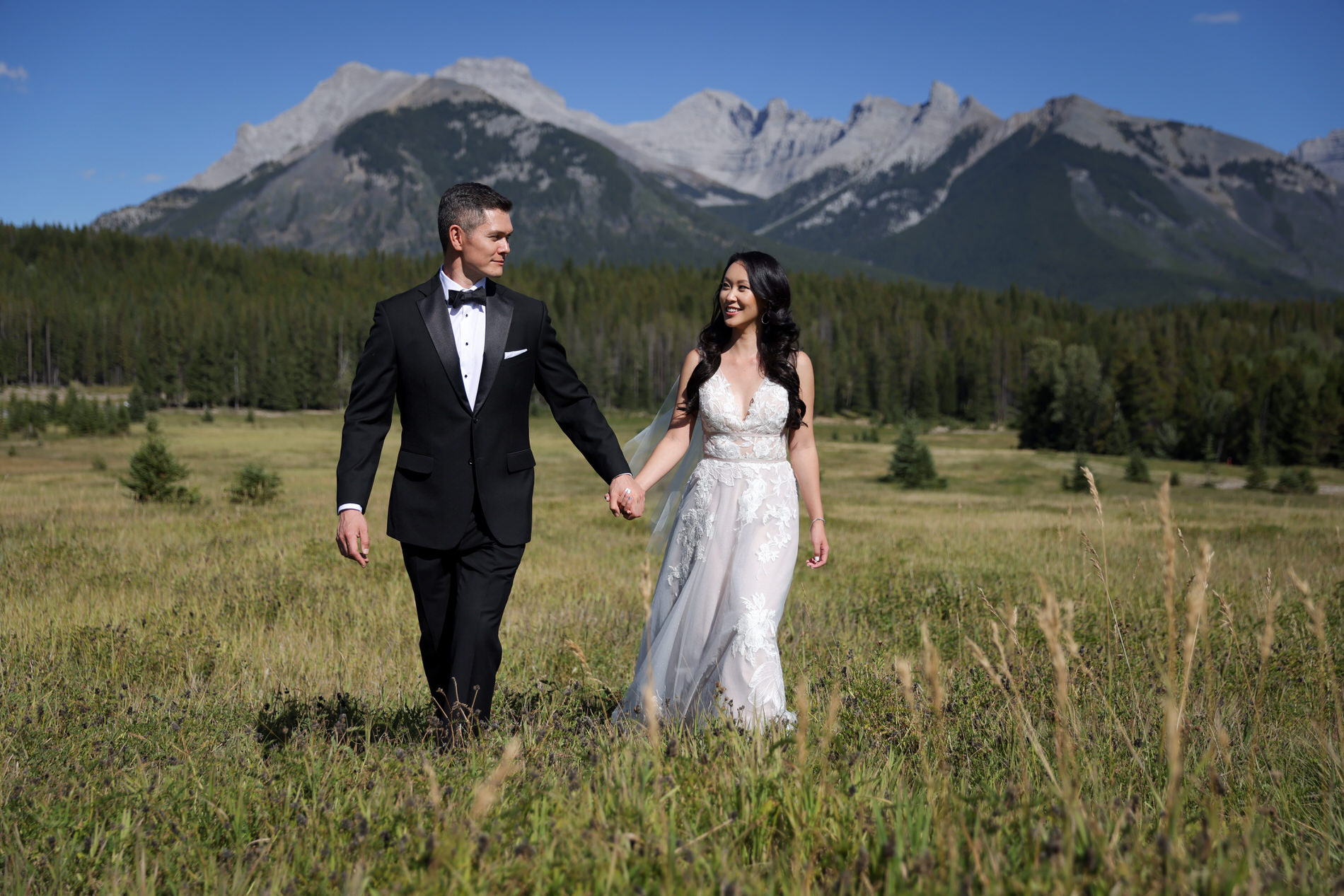 Bride and groom take photos in a field during the fall in Banff, AB