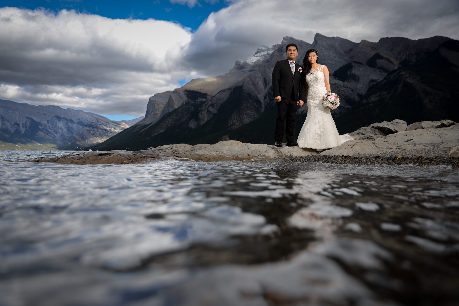 Bride and groom take amazing wedding photos at Lake Minnewanka in Banff, AB
