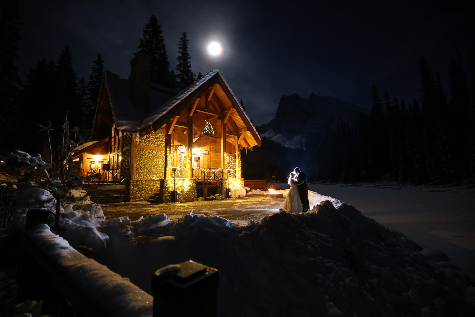 Bride and groom take a night photo at Emerald Lake lodge during their wedding with stars mountains and moon